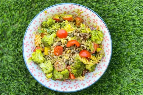 Ensalada de pasta con brócoli, tomates cherry y semillas. Los ingredientes frescos y coloridos la hacen irresistible.